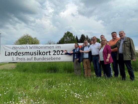 Banner Landmusikpreis mit Fehler am Ortseingang Ötigheim mit Bürgermeister und Vereinsvorständen.