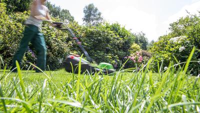 ILLUSTRATION - Eine Frau maeht am 13.07.2018 in einem Garten in Hamburg den Rasen mit einem Rasenmaeher (gestellte Szene). Foto: Christin Klose || Modellfreigabe vorhanden