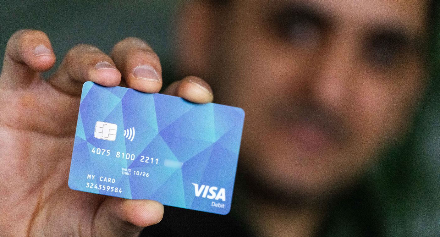 Ein Geflüchteter hält eine Debitcard in der Hand.