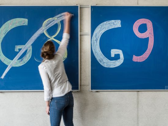 Eine Schülerin der Oberstufe streicht an einem Gymnasium den Schriftzug „G8“ an einer Tafel durch, daneben lässt sie „G9“ unberührt.
