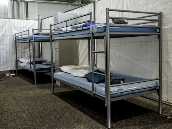Stockbetten sind zwischen Trennwänden aus Planen in einer Messehalle für die Unterbringung von Schutzsuchenden aus der Ukraine aufgebaut.