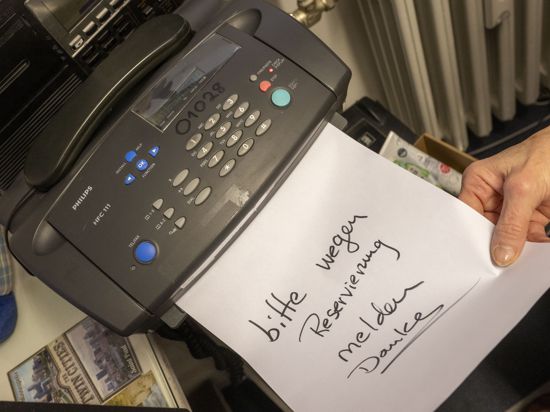 ILLUSTRATION - Eine Frau schiebt ein beschriftetes Papier in ein Faxgerät. Fabian Mehring (Freie Wähler), Minister für Digitales, will Faxe in Bayerns Behörden abschaffen. (zu dpa "Digitalminister Mehring will Faxe in Behörden abschaffen") +++ dpa-Bildfunk +++