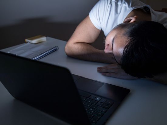 Ein Jugendlicher schläft vor dem Computer ein.