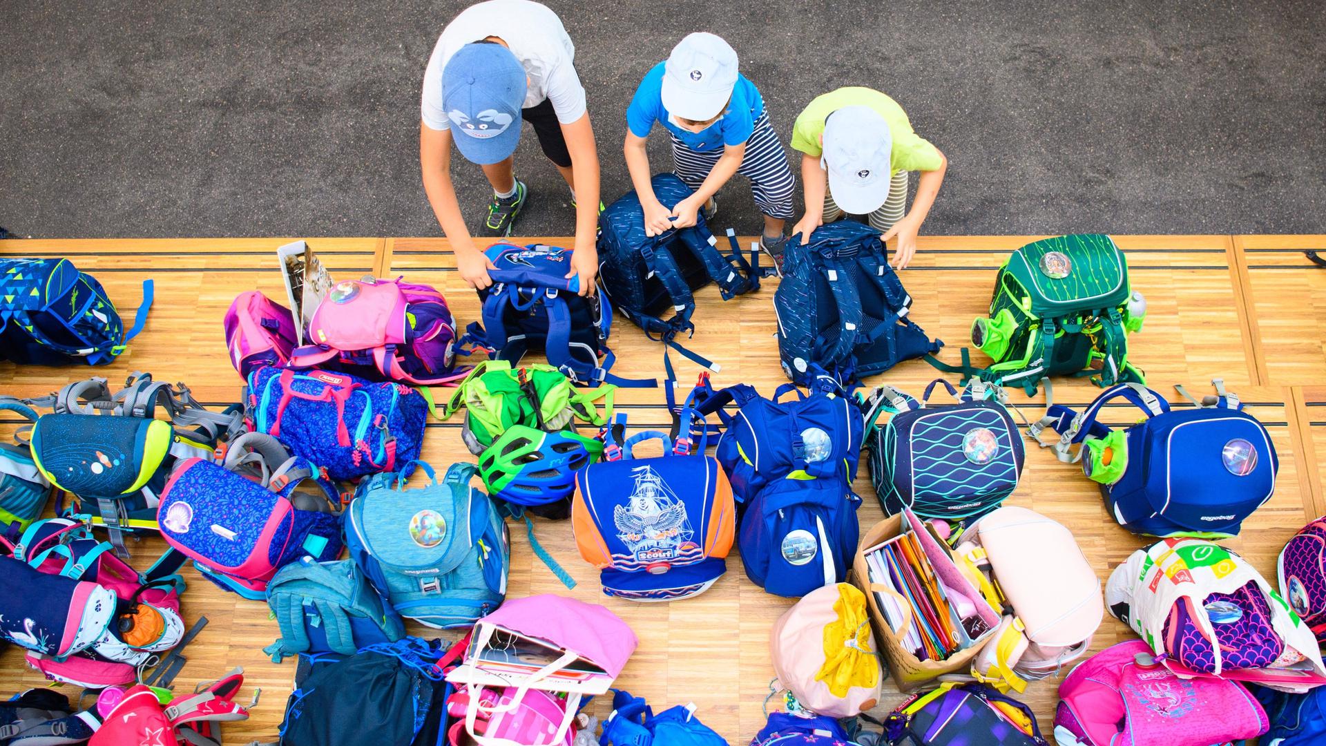 Drei Erstklässler stellen in der Grundschule „Am Jungfernsee“ auf einem Podest ihre Schultaschen ab. (Zu dpa "Grüne pochen auf Recht auf Ganztagsbetreuung für Grundschulkinder") +++ dpa-Bildfunk +++