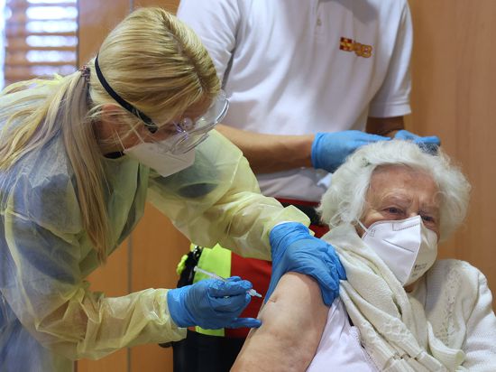 Eine Mitarbeiterin impft eine Seniorin gegen das Coronavirus. 