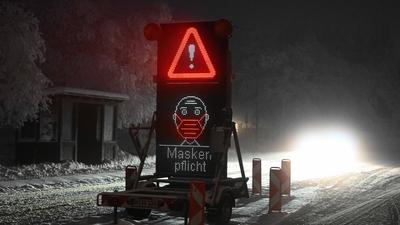 Ein Verkehrsschild mit dem Hinweis «Maskenpflicht» steht auf einer Zufahrt zu einem Parkplatz.