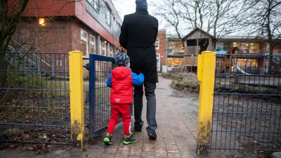 Ein Vater begleitet sein Kind auf das Gelände einer Kindertagesstätte. Von Montag an schränkt Hamburg den Betrieb seiner Kitas weiter ein. Aus dem derzeit eingeschränkten Regelbetrieb wird eine erweiterte Notbetreuung. +++ dpa-Bildfunk +++