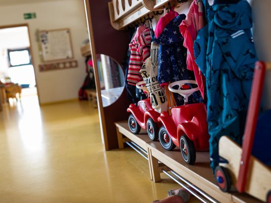 Bobbycars stehen unter Jacken von Kindern, die an einer Garderobe einer Kindertagesstätte (Kita) hängen. 