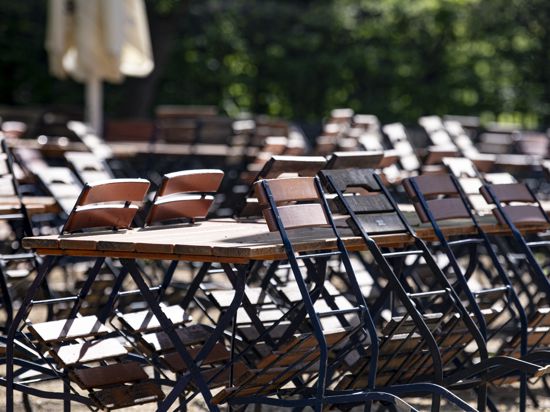 Mehrere Stühle sind in einem geschlossenen Biergarten im Tiergarten an die Tische angelehnt.