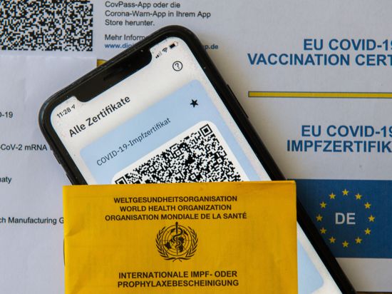 Ein Impfpass und ein Smartphone, auf dem die App CovPass läuft, liegen auf einem Impfzertifikat, das von einer Apotheke ausgestellt wurde. Der digitale Nachweis ist eine freiwillige Ergänzung des weiter gültigen gelben Impfheftes aus Papier. Deutschland setzt damit ein Vorhaben der Europäischen Union um. +++ dpa-Bildfunk +++
