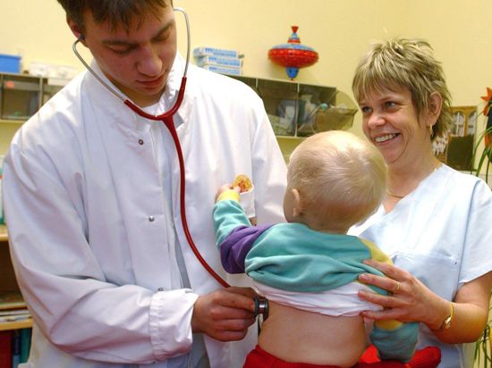 Ein Kinderarzt hört ein Kleinkind ab.
