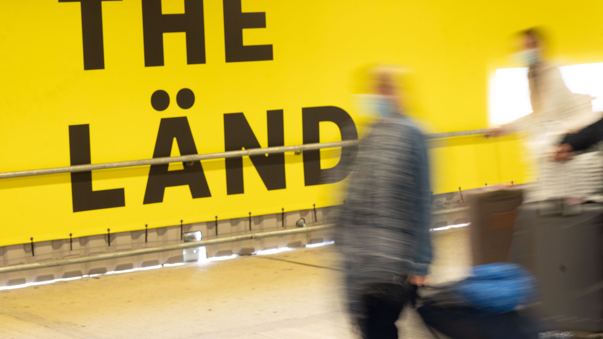 Menschen laufen im Hauptbahnhof von Stuttgart an einer Werbekampagne für das Land Baden-Württemberg mit dem Titel „The Länd“ vorbei. Damit soll um Fachkräfte geworben werden.