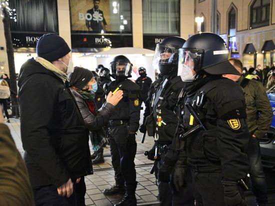 Leute in der Mannheimer Innenstadt sprechen mit Polizisten in Schutzausrüstung. 