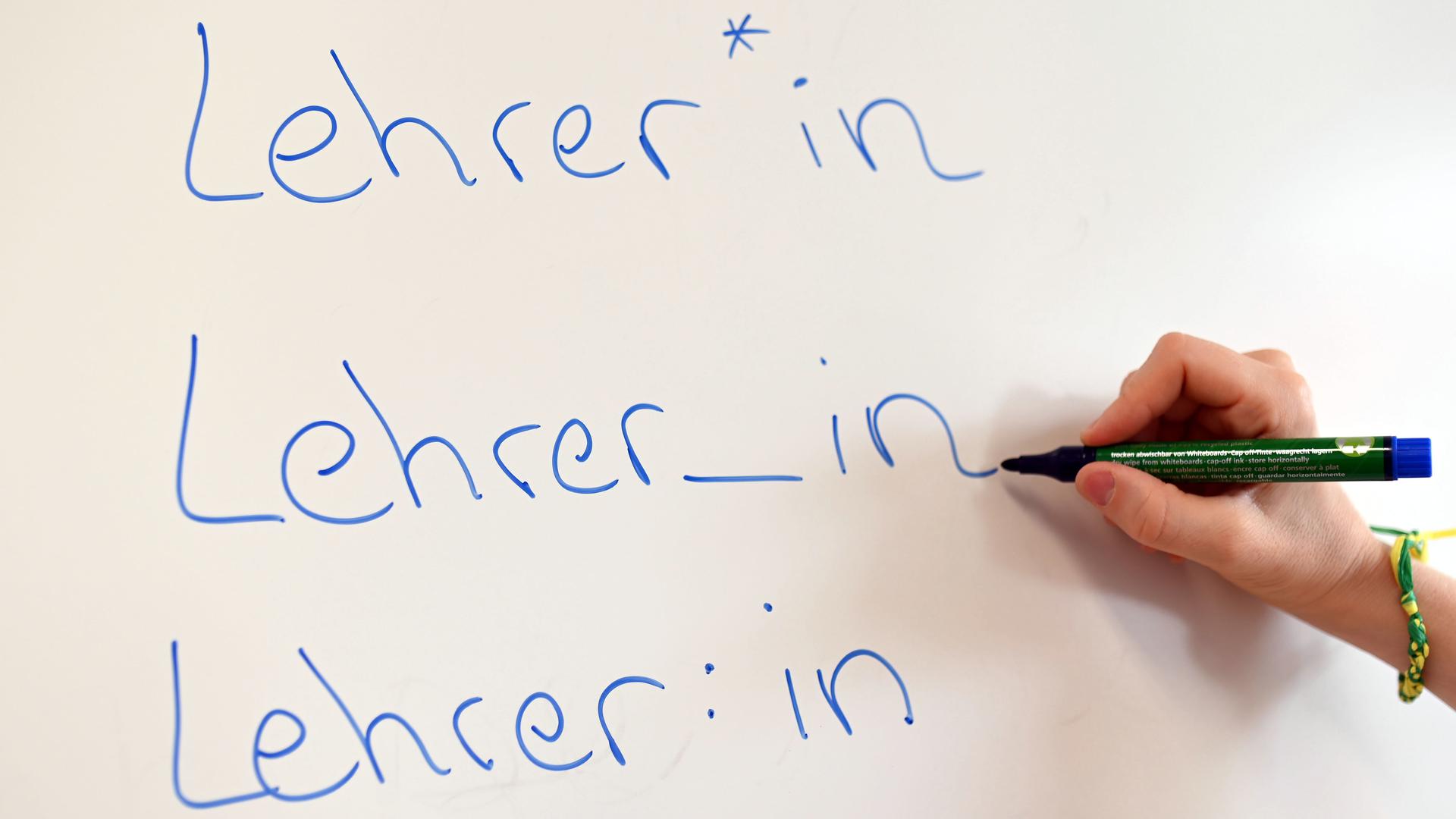 An einem Whiteboard steht das Wort Lehrer in verschiedenen Gender-Schreibweisen. 
