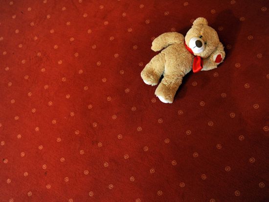 Ein Teddybär liegt verloren auf einem Teppich (Symbolbild).