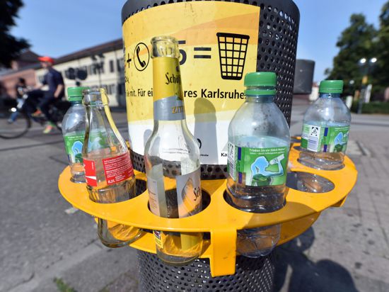 ILLUSTRATION ? An einem Mülleimer in der Innenstadt von Karlsruhe (Baden-Württemberg) ist am 06.08.2014 ein Pfandring angebracht in dem leere Flaschen stehen. Wer seine Pfandflaschen oder -dosen nicht ins Geschäft zurückbringen möchte, kann sie in die Ringe stecken. So ist es Pfandsammlern einfacher möglich, die Flaschen und Dosen mitzunehmen. Sie müssen nicht mehr in die Abfallbehälter hineingreifen und den Müll durchwühlen. Foto: Uli Deck/dpa (zu lsw-Korr "Südweststädte diskutieren über Ablegestellen für Pfandflaschen" vom 25.11.2014) +++(c) dpa - Bildfunk+++