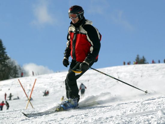 Ein Skifahrer fährt auf einer Piste am Feldberg im Schwarzwald. Sonnenschein und strahlend blauer Himmel bieten hervorragende Bedingungen für eine Skiabfahrt. 