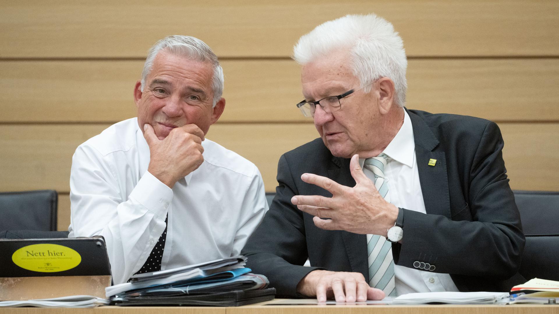 Winfried Kretschmann (Bündnis 90/Die Grünen, rchts), Ministerpräsident von Baden-Württemberg, und Thomas Strobl (CDU), Innenminister von Baden-Württemberg, unterhalten sich am Rande einer Plenarsitzung im Landtag von Baden-Württemberg.