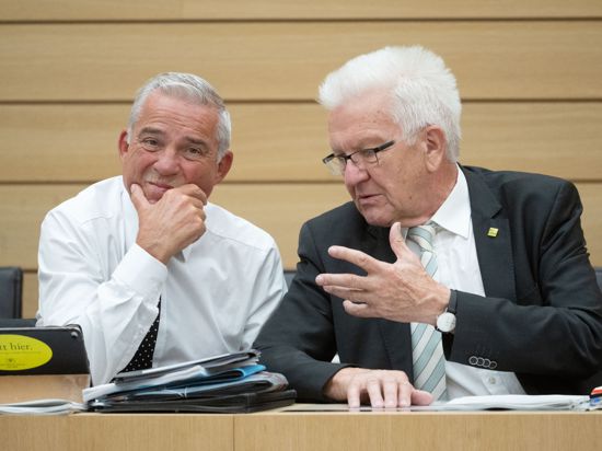 Winfried Kretschmann (Bündnis 90/Die Grünen, rchts), Ministerpräsident von Baden-Württemberg, und Thomas Strobl (CDU), Innenminister von Baden-Württemberg, unterhalten sich am Rande einer Plenarsitzung im Landtag von Baden-Württemberg.