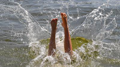Ein Mann macht einen Kopfsprung in das Wasser eines Strandbads.