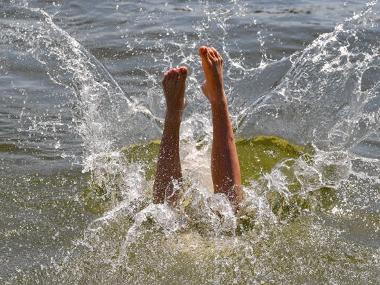 Ein Mann macht einen Kopfsprung in das Wasser eines Strandbads.