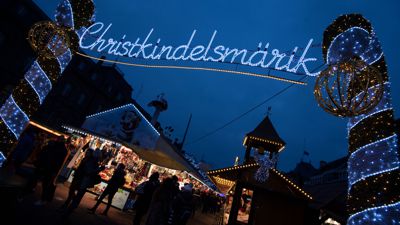 Das Wort "Christkindelsmärik" prangt in großen beleuchteten Buchstaben an einem Zugang zum Weihnachtsmarkt.
