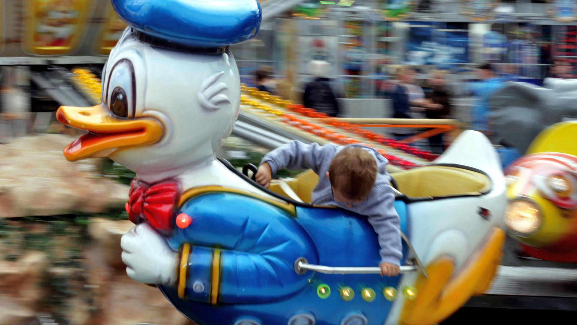 Kinderkarussell im Donald Duck Motiv mit einem Kind darin.