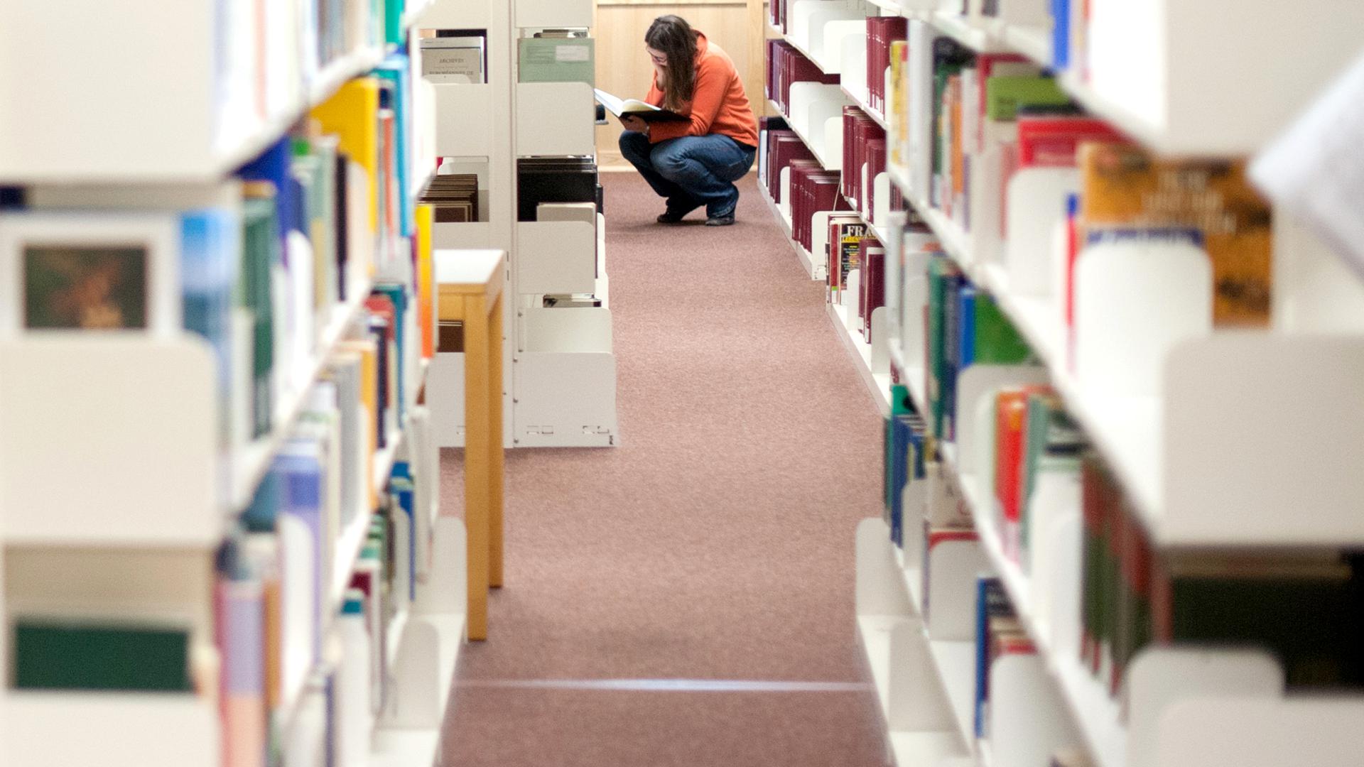 Eine Studentin sucht ein Buch in einer Bibliothek.
