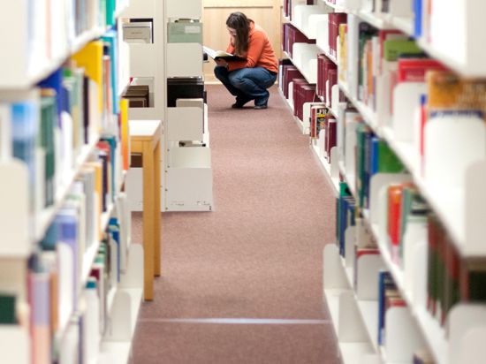 Eine Studentin sucht ein Buch in einer Bibliothek.