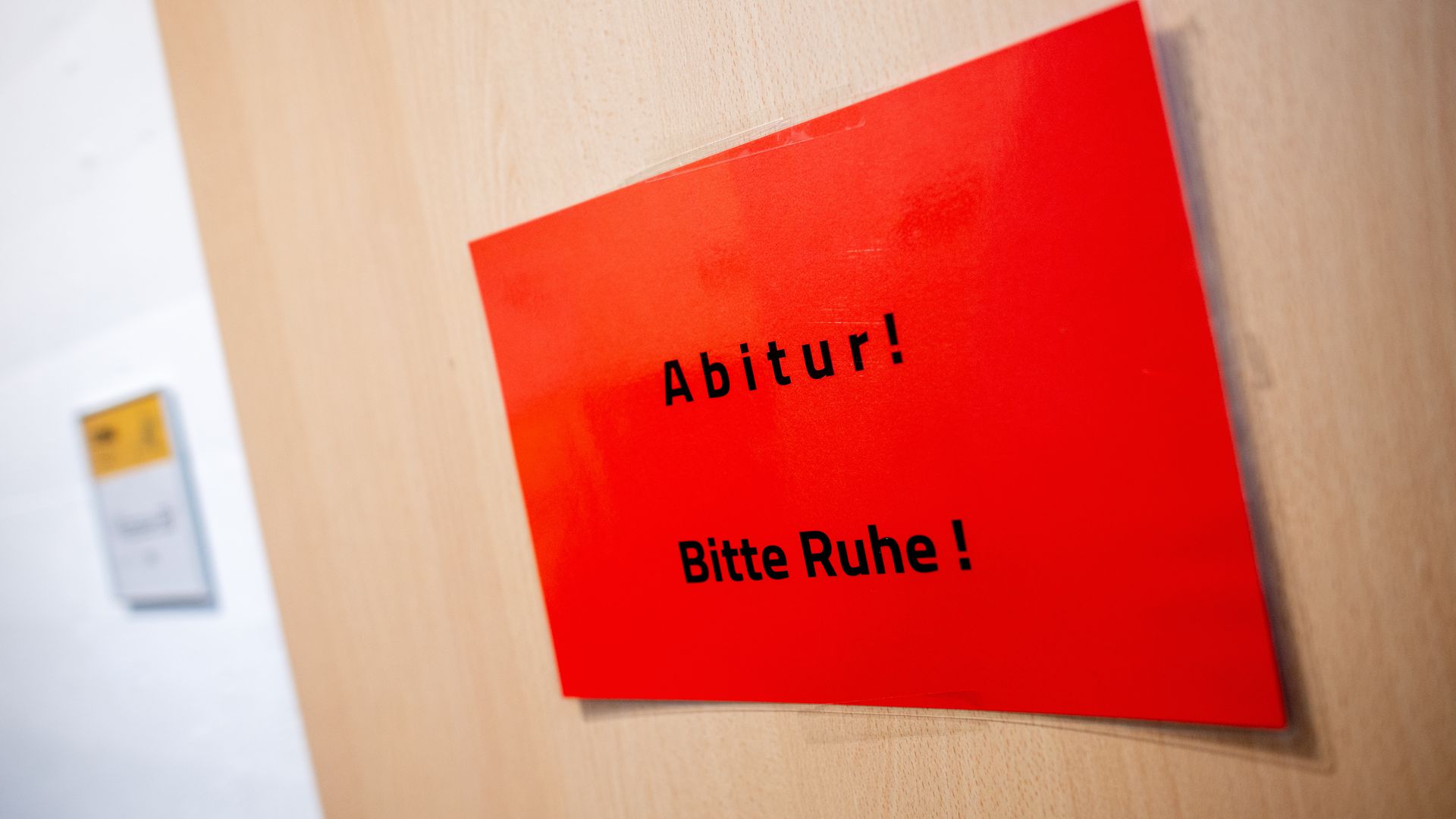 Ein Schild mit der Aufschrift "Abitur! Bitte Ruhe!" hängt während der schriftlichen Abiturprüfungen im Fach Geschichte an einer Tür in einer Schule.