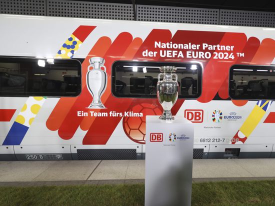 Der Pokal der Fußball-EM steht vor einem ICE der Deutschen Bahn, mit Sonderlackierung zur EM 2024.