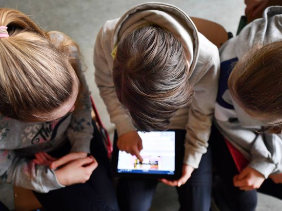 Schüler arbeiten mit einem Tablet. 