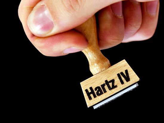 Eine Hand hält einen Stempel mit der Aufschrift "Hartz IV". 