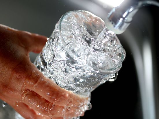 Trinkwasser läuft aus einem Wasserhahn in ein Glas.