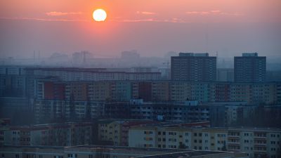 Die Sonne geht hinter zahlreichen Hochhäusern in dem Berlin-Marzahn unter. Rechts im Dunst ist der Berliner Fernsehturm zu sehen.