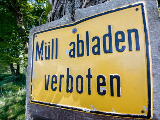 Ein Schild mit der Aufschrift "Müll abladen verboten" in einem Waldstück.