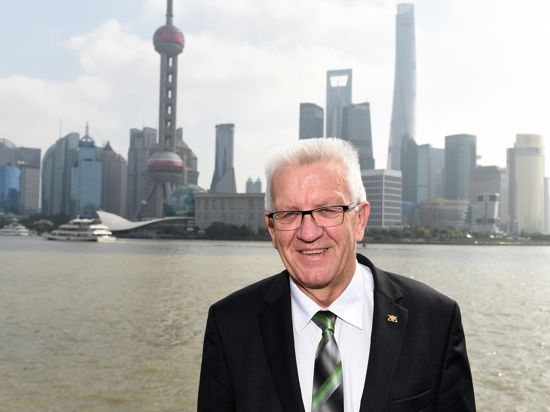 Baden-Württembergs Ministerpräsident Winfried Kretschmann steht am Promenadenabschnitt „Bund“ in Shanghai vor der Skyline der Stadt. 