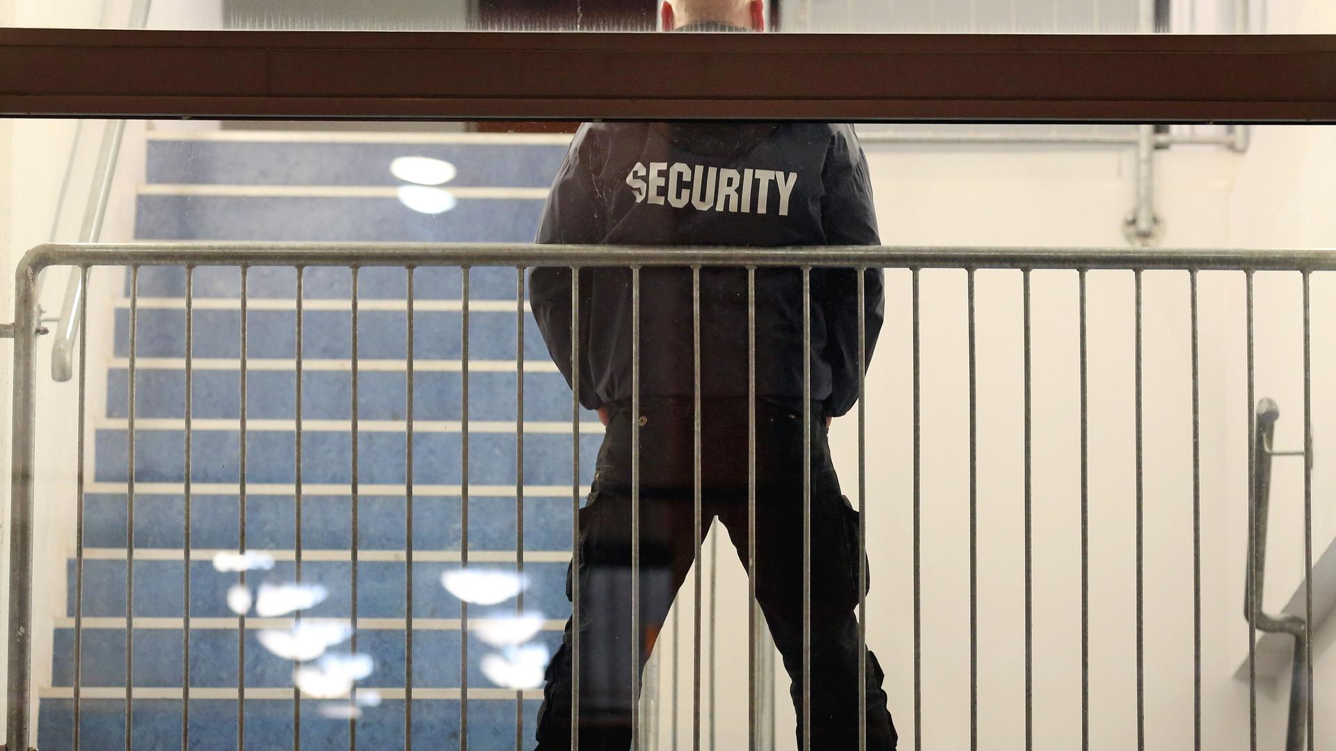 Ein Mitarbeiter einer Security-Firma steht in einem Treppenhaus.