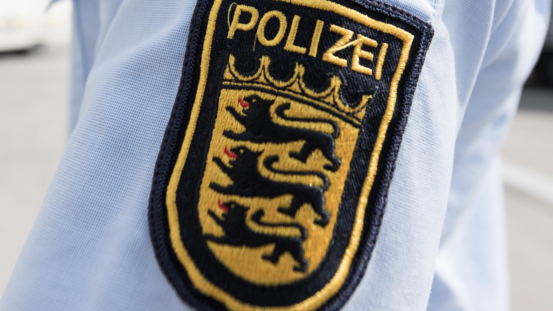 Ein Dienstwappen der Polizei ist an einem Hemd eines Polizisten aufgenäht.