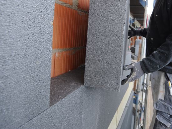 Ein Mann montiert am Donnerstag (04.11.2010) eine Styroporplatte zur Wärmedämmung an die Fassade eines Hauses.