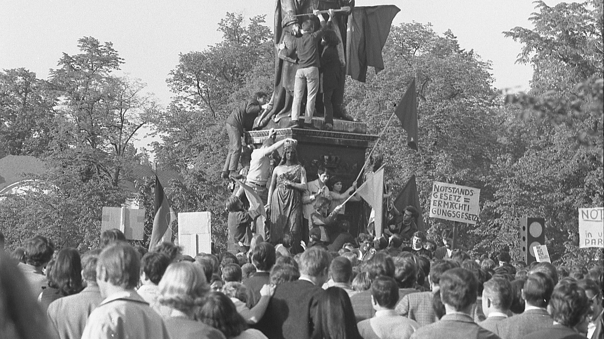 In Karlsruhe demonstrieren Studenten am 15. Mai 1968 vor dem Denkmal für Großherzog Karl Friedrich von Baden gegen die umstrittenen Notstandsgesetze.

Foto: Stadtarchiv Karlsruhe 8/BA Schlesiger A15/176/7/24a