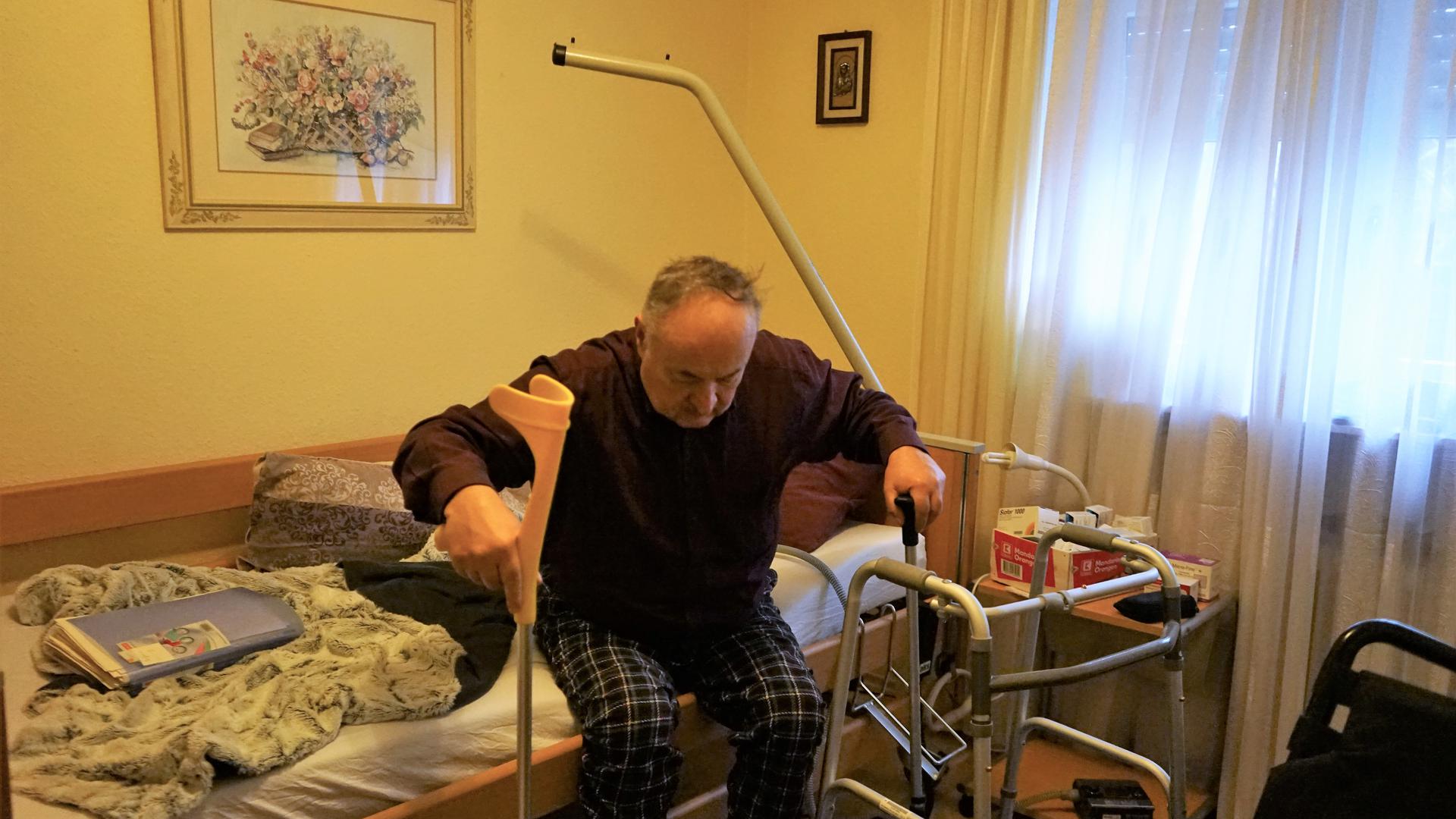 Sergiy Kelm, Rentner aus Iffezheim, sitzt auf seinem Pflegebett und versucht aufzustehen