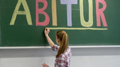 Eine Schülerin unterstreicht das Wort „Abitur“ an einer Tafel.