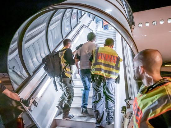 Polizeibeamte begleiten einen Afghanen auf dem Flughafen Leipzig-Halle in ein Charterflugzeug. 45 abgelehnte Asylbewerber wurden mit dem Sonderflug in Afghanistans Hauptstadt Kabul abgeschoben.(zu dpa-Story: Abschiebeflug nach Afghanistan) +++ dpa-Bildfunk +++