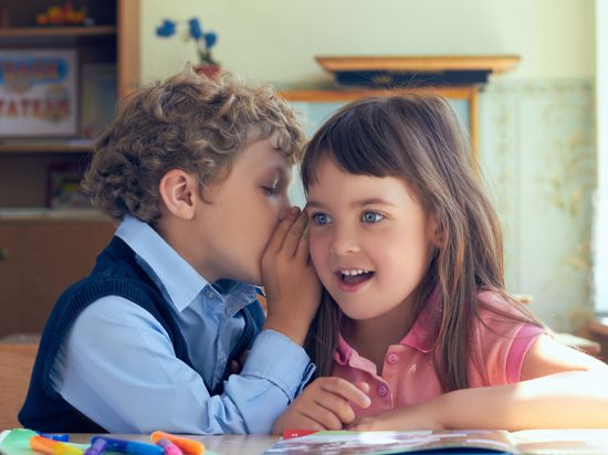 Pupils whispering secrets during class at the elementary school.