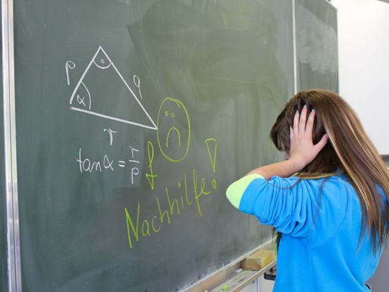 Kind verzweifelt an der Schultafal an einer Mathematik-Aufgabe