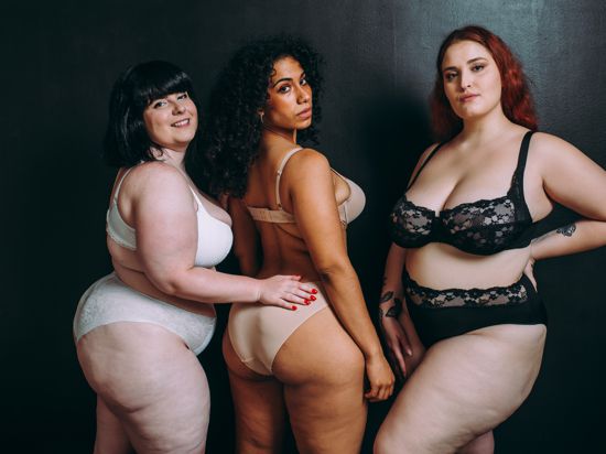 Drei mehrgewichtige Frauen schauen für ein Fotoprojekt selbstbewusst in die Kamera. 