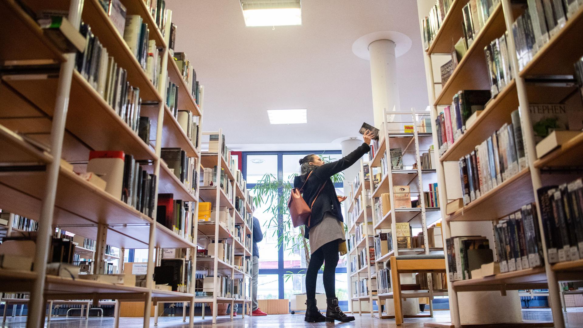 Eine Besucherin der Stadtbücherei nimmt ein Buch aus dem Regal. Die Stadtbücherei in Geislingen an der Steige wird mit der Auszeichnung «Bibliothek des Jahres Baden Württemberg» geehrt. (zu dpa "Totgesagte leben länger - Bibliotheken im Zeitalter des Internets") +++ dpa-Bildfunk +++
