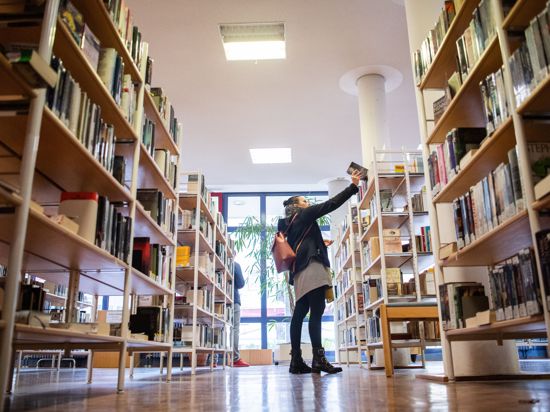Eine Besucherin der Stadtbücherei nimmt ein Buch aus dem Regal. Die Stadtbücherei in Geislingen an der Steige wird mit der Auszeichnung «Bibliothek des Jahres Baden Württemberg» geehrt. (zu dpa "Totgesagte leben länger - Bibliotheken im Zeitalter des Internets") +++ dpa-Bildfunk +++