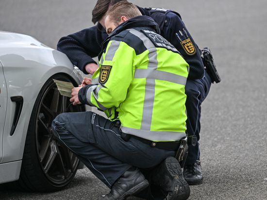 Polizisten kontrollieren ein Auto, das von einer Verkehrskontrolle am sogenannten Car-Freitag herausgezogen wurde.